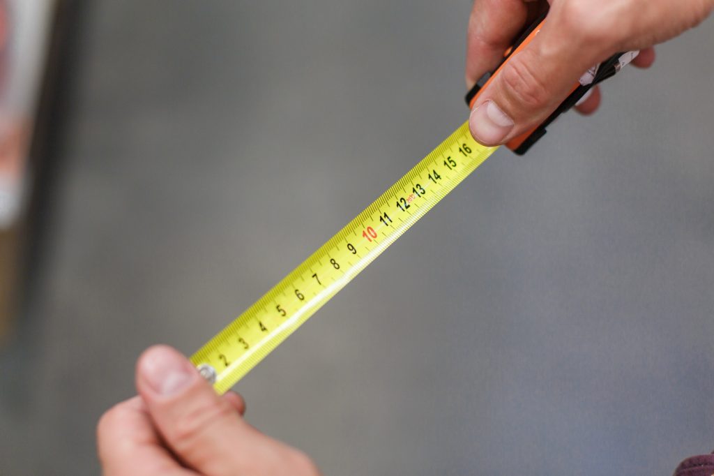 Construction tape. Measurement. The man measures with a tape measure.