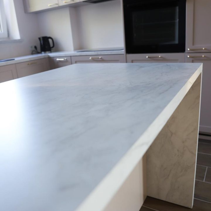 Kuchnia na wymiar w Warszawie – układ L, wyspa, witryna i szafa. Subtelna kolorystyka, marmurowe blaty i złote detale. Realizacja MiD Prestige w 8 tygodni.