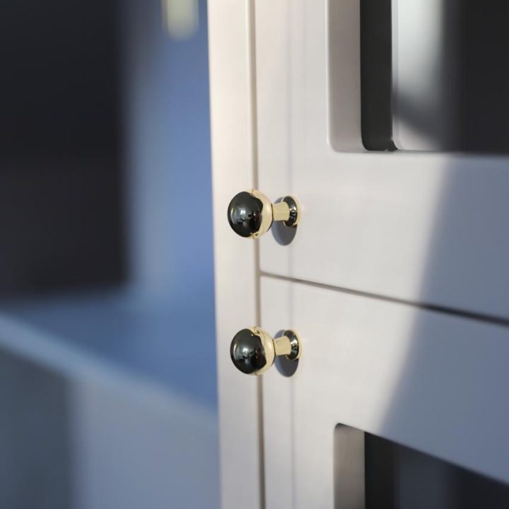 Kuchnia na wymiar w Warszawie – układ L, wyspa, witryna i szafa. Subtelna kolorystyka, marmurowe blaty i złote detale. Realizacja MiD Prestige w 8 tygodni.