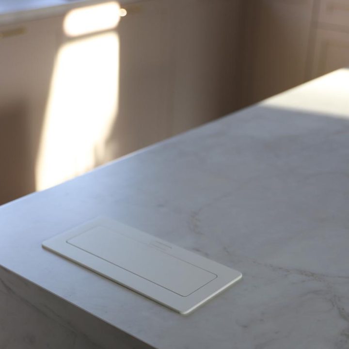 Kuchnia na wymiar w Warszawie – układ L, wyspa, witryna i szafa. Subtelna kolorystyka, marmurowe blaty i złote detale. Realizacja MiD Prestige w 8 tygodni.