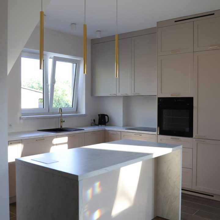 Kuchnia na wymiar w Warszawie – układ L, wyspa, witryna i szafa. Subtelna kolorystyka, marmurowe blaty i złote detale. Realizacja MiD Prestige w 8 tygodni.