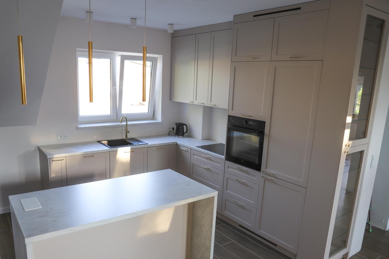 Kuchnia na wymiar w Warszawie – układ L, wyspa, witryna i szafa. Subtelna kolorystyka, marmurowe blaty i złote detale. Realizacja MiD Prestige w 8 tygodni.