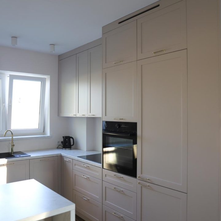 Kuchnia na wymiar w Warszawie – układ L, wyspa, witryna i szafa. Subtelna kolorystyka, marmurowe blaty i złote detale. Realizacja MiD Prestige w 8 tygodni.