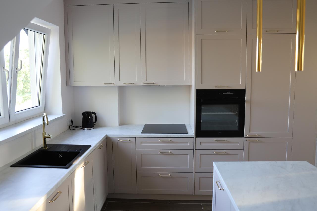 Kuchnia na wymiar w Warszawie – układ L, wyspa, witryna i szafa. Subtelna kolorystyka, marmurowe blaty i złote detale. Realizacja MiD Prestige w 8 tygodni.