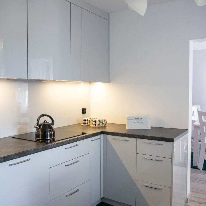Nowoczesna kuchnia na wymiar w Słupsku – wyspa, wysoka zabudowa i szafki w dwóch głębokościach. Fronty akrylowe w szarym połysku i perfekcyjne dopasowanie. MiD Meble. MiD Faast Fit.