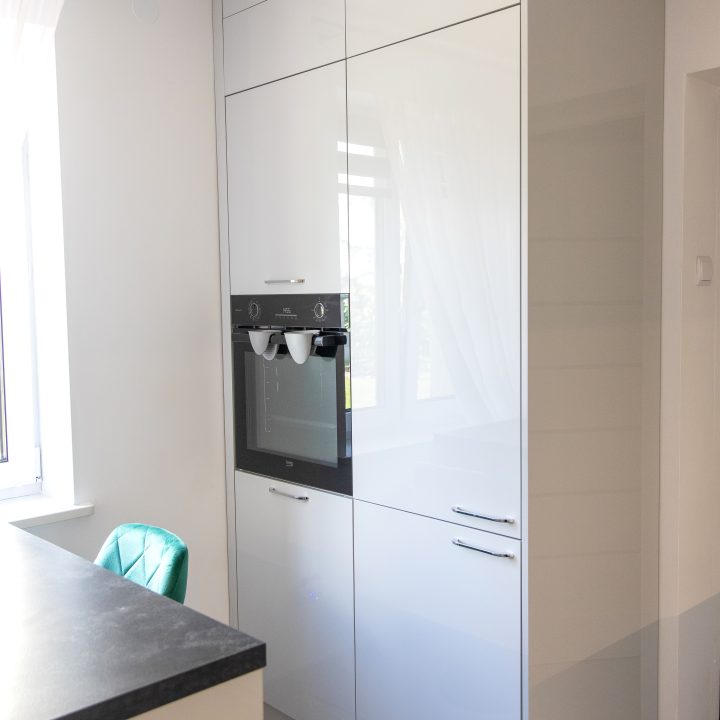 Nowoczesna kuchnia na wymiar w Słupsku – wyspa, wysoka zabudowa i szafki w dwóch głębokościach. Fronty akrylowe w szarym połysku i perfekcyjne dopasowanie. MiD Meble. MiD Faast Fit.