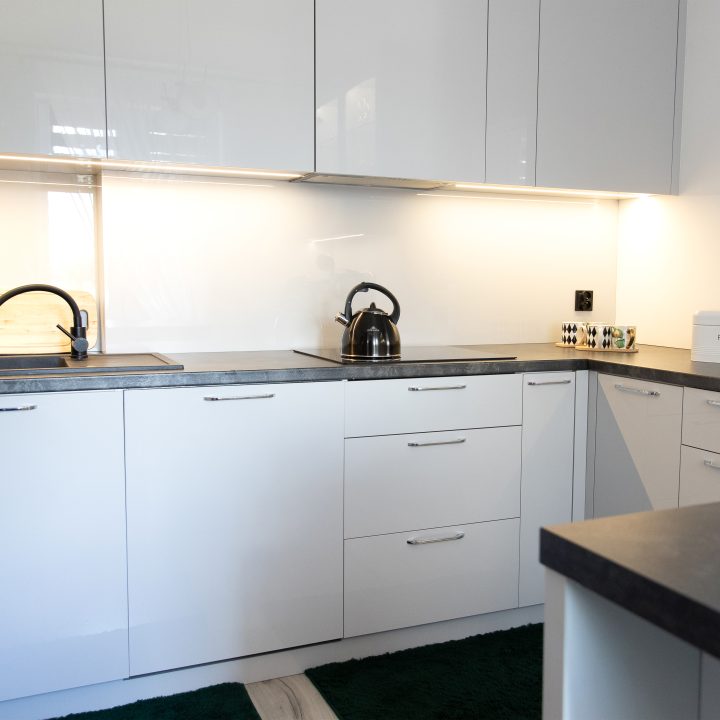 Nowoczesna kuchnia na wymiar w Słupsku – wyspa, wysoka zabudowa i szafki w dwóch głębokościach. Fronty akrylowe w szarym połysku i perfekcyjne dopasowanie. MiD Meble. MiD Faast Fit.