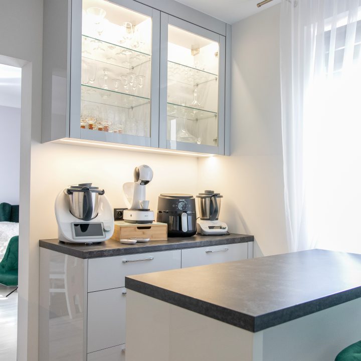 Nowoczesna kuchnia na wymiar w Słupsku – wyspa, wysoka zabudowa i szafki w dwóch głębokościach. Fronty akrylowe w szarym połysku i perfekcyjne dopasowanie. MiD Meble. MiD Faast Fit.