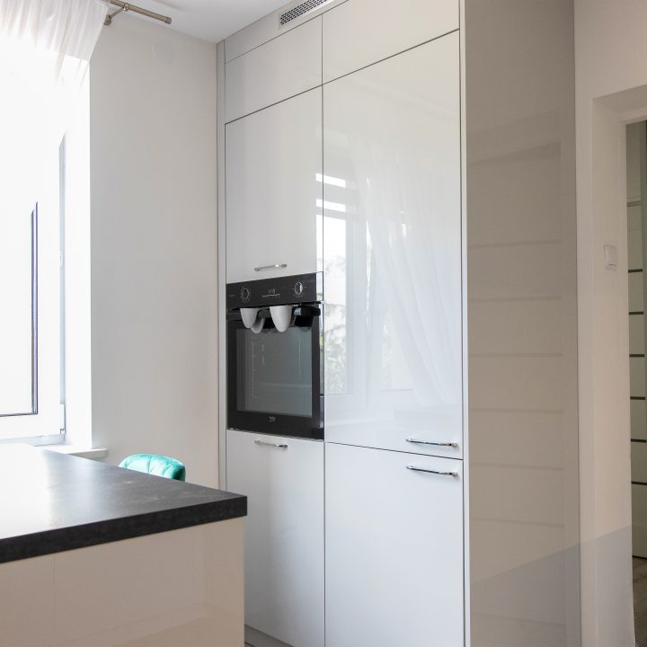 Nowoczesna kuchnia na wymiar w Słupsku – wyspa, wysoka zabudowa i szafki w dwóch głębokościach. Fronty akrylowe w szarym połysku i perfekcyjne dopasowanie. MiD Meble. MiD Faast Fit.