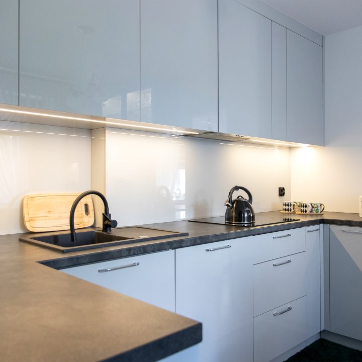 Nowoczesna kuchnia na wymiar w Słupsku – wyspa, wysoka zabudowa i szafki w dwóch głębokościach. Fronty akrylowe w szarym połysku i perfekcyjne dopasowanie. MiD Meble. MiD Faast Fit.