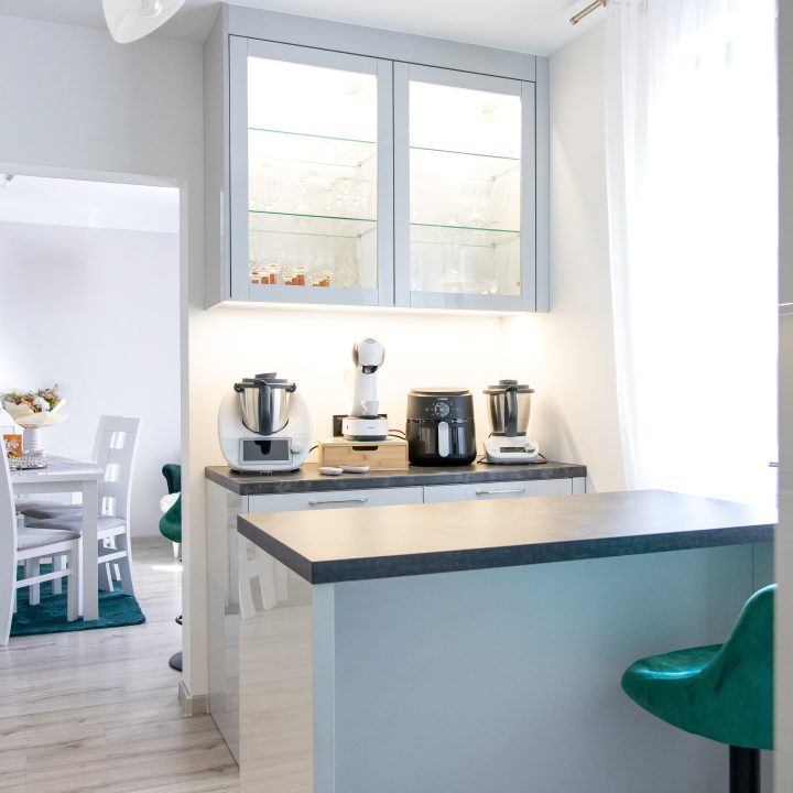 Nowoczesna kuchnia na wymiar w Słupsku – wyspa, wysoka zabudowa i szafki w dwóch głębokościach. Fronty akrylowe w szarym połysku i perfekcyjne dopasowanie. MiD Meble. MiD Faast Fit.