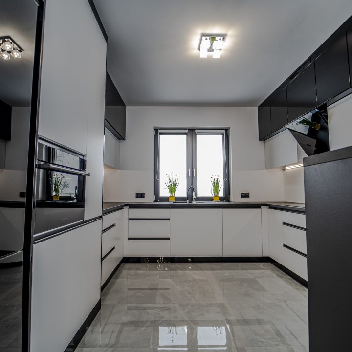 Nowoczesna kuchnia na wymiar w Pułtusku – biel i czerń w połysku, wyspa, oświetlenie LED i szafa we wiatrołapie. Styl, ergonomia i trwałość w pakiecie MiD Smart.