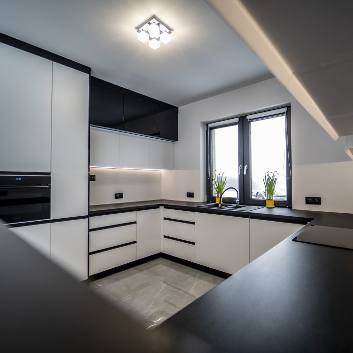 Nowoczesna kuchnia na wymiar w Pułtusku – biel i czerń w połysku, wyspa, oświetlenie LED i szafa we wiatrołapie. Styl, ergonomia i trwałość w pakiecie MiD Smart.