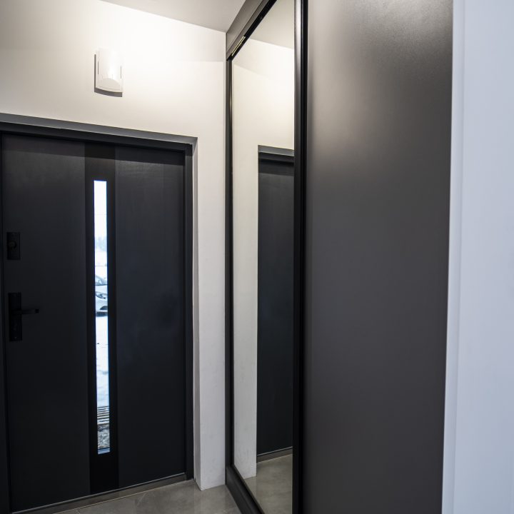 Nowoczesna kuchnia na wymiar w Pułtusku – biel i czerń w połysku, wyspa, oświetlenie LED i szafa we wiatrołapie. Styl, ergonomia i trwałość w pakiecie MiD Smart.