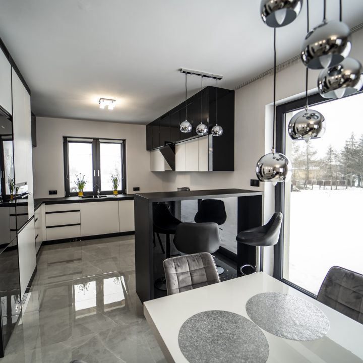 Nowoczesna kuchnia na wymiar w Pułtusku – biel i czerń w połysku, wyspa, oświetlenie LED i szafa we wiatrołapie. Styl, ergonomia i trwałość w pakiecie MiD Smart.