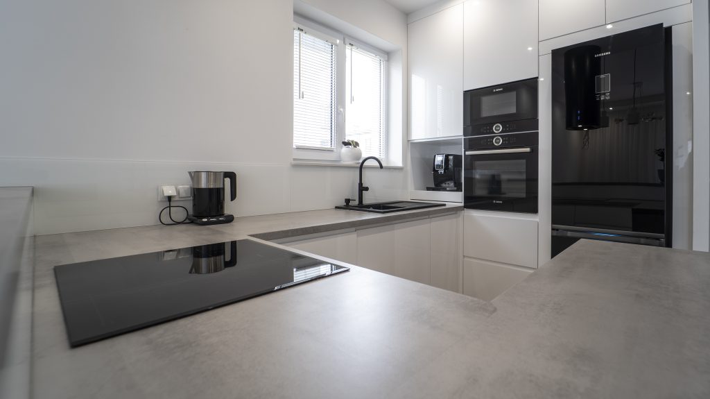 Kuchnia na wymiar Ożarów Mazowiecki – białe fronty w połysku, betonowy blat i wyspa dwupoziomowa. Styl, ergonomia i jakość w pakiecie MiD Smart.