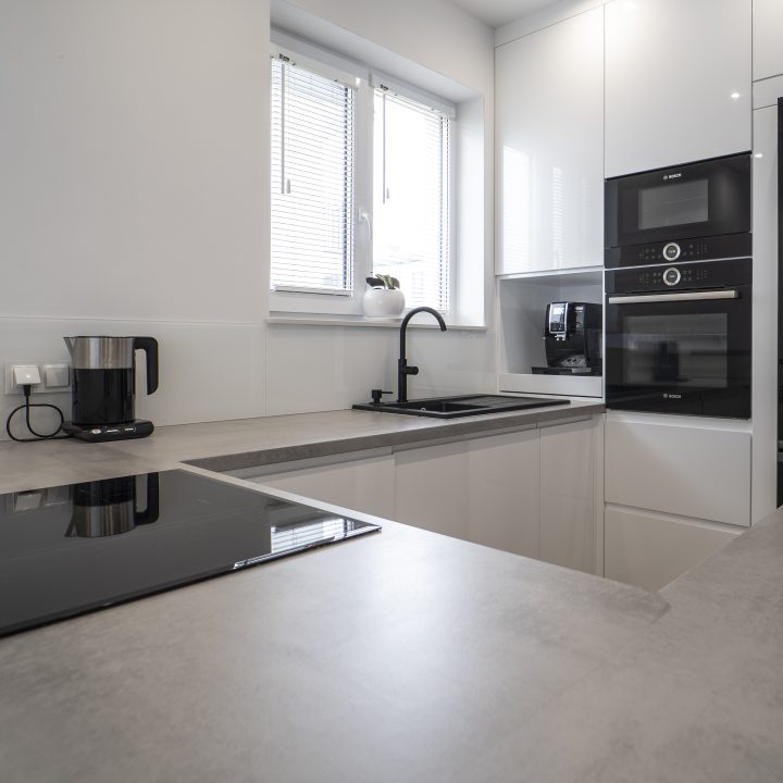 Kuchnia na wymiar Ożarów Mazowiecki – białe fronty w połysku, betonowy blat i wyspa dwupoziomowa. Styl, ergonomia i jakość w pakiecie MiD Smart.