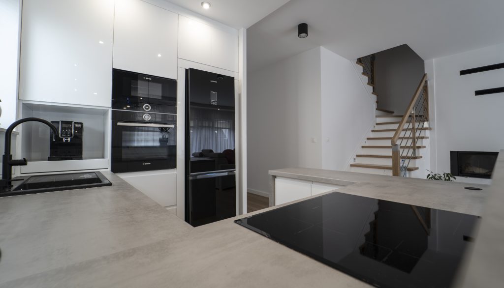 Kuchnia na wymiar Ożarów Mazowiecki – białe fronty w połysku, betonowy blat i wyspa dwupoziomowa. Styl, ergonomia i jakość w pakiecie MiD Smart.