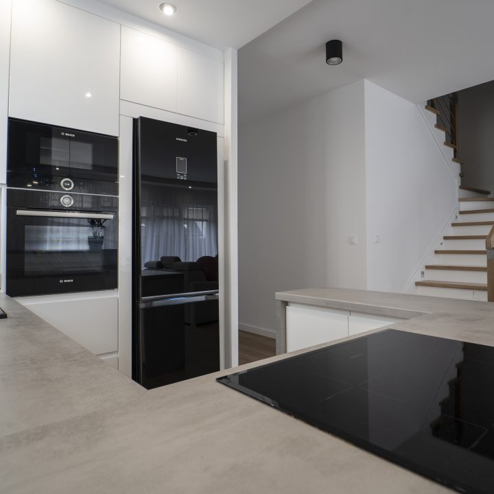 Kuchnia na wymiar Ożarów Mazowiecki – białe fronty w połysku, betonowy blat i wyspa dwupoziomowa. Styl, ergonomia i jakość w pakiecie MiD Smart.
