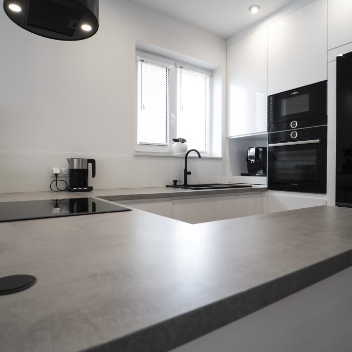 Kuchnia na wymiar Ożarów Mazowiecki – białe fronty w połysku, betonowy blat i wyspa dwupoziomowa. Styl, ergonomia i jakość w pakiecie MiD Smart.